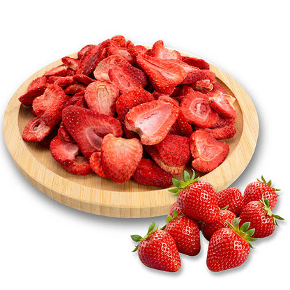 Dried strawberries on a wooden plate with fresh strawberries on a white background