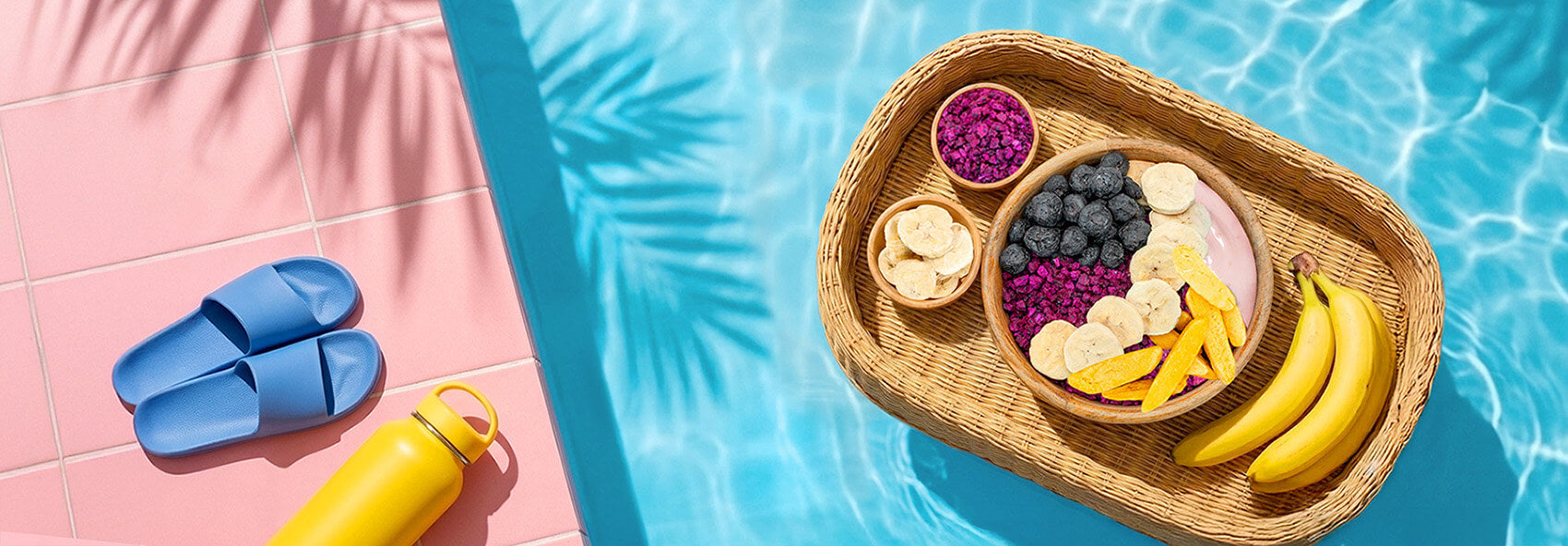 Wicker tray with fruit yogurt by a poolside on a pink deck